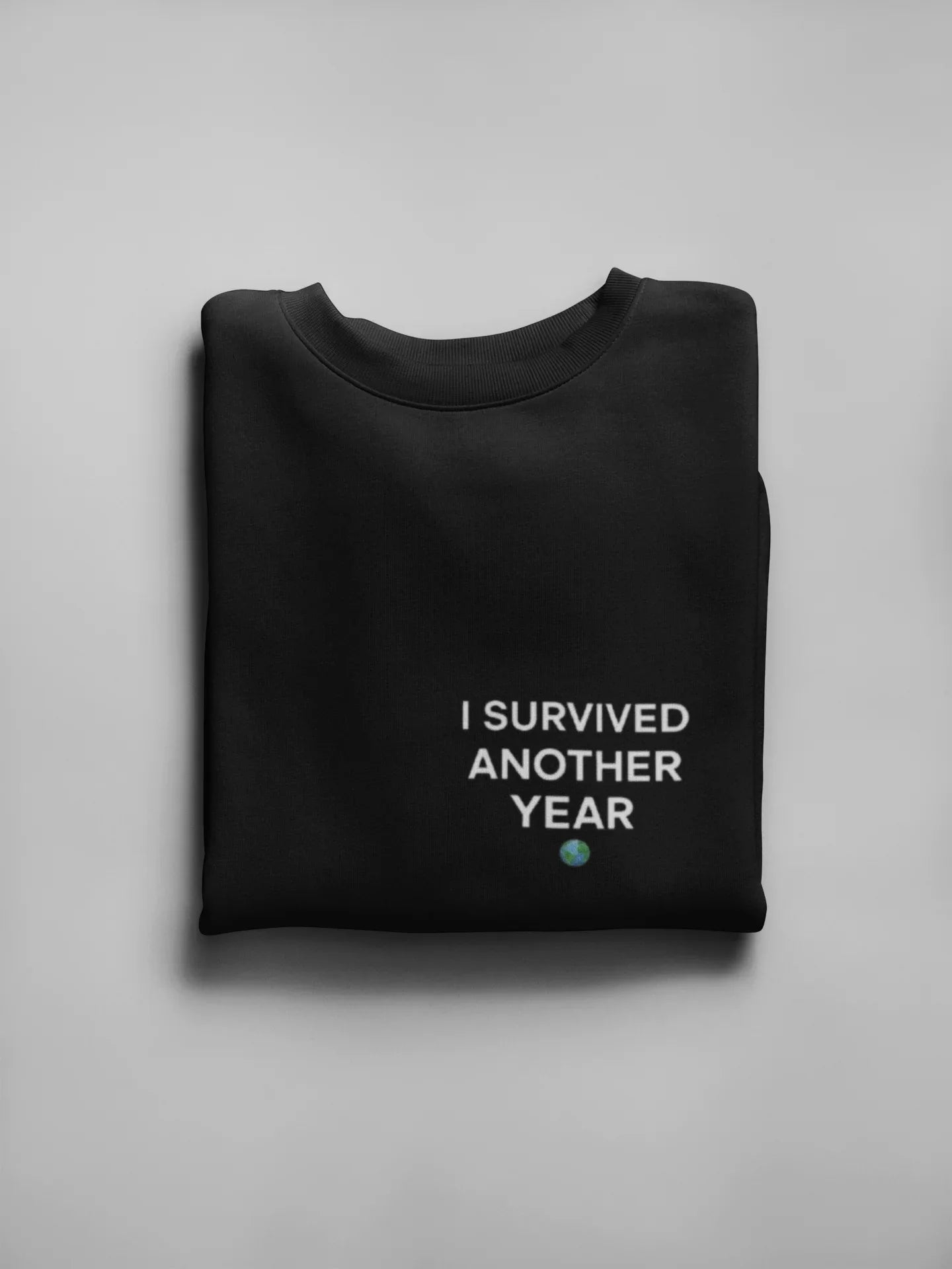 Black crewneck sweatshirt with front text graphic reading “I SURVIVED ANOTHER YEAR”