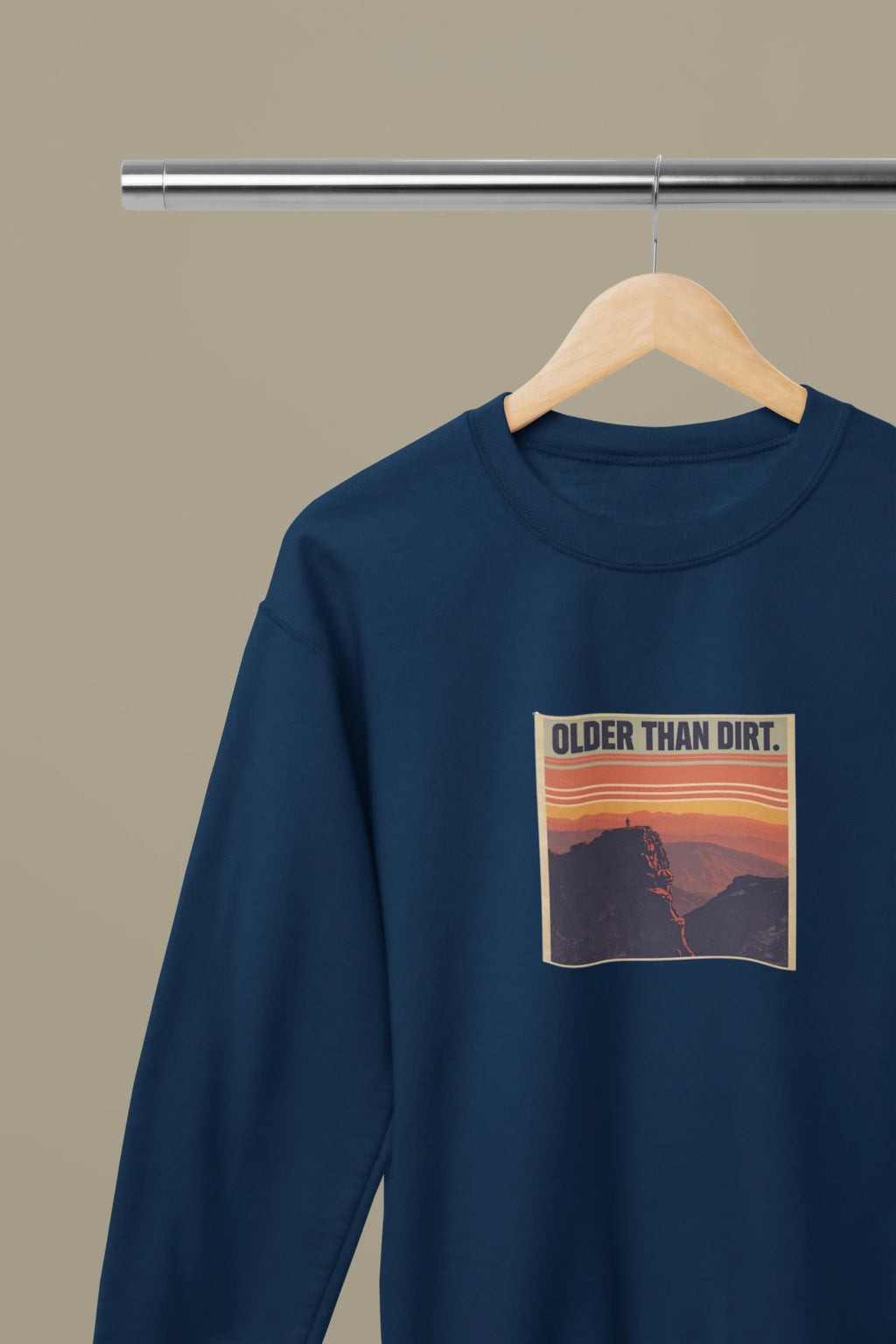 Navy crewneck sweatshirt with “OLDER THAN DIRT.” graphic on hanger