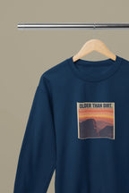 Navy crewneck sweatshirt with “OLDER THAN DIRT.” graphic on hanger