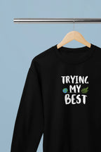 Black crewneck sweatshirt with "Trying My Best" text graphic on the chest