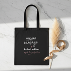 Black canvas tote bag with 'not old vintage' and 'limited edition' print