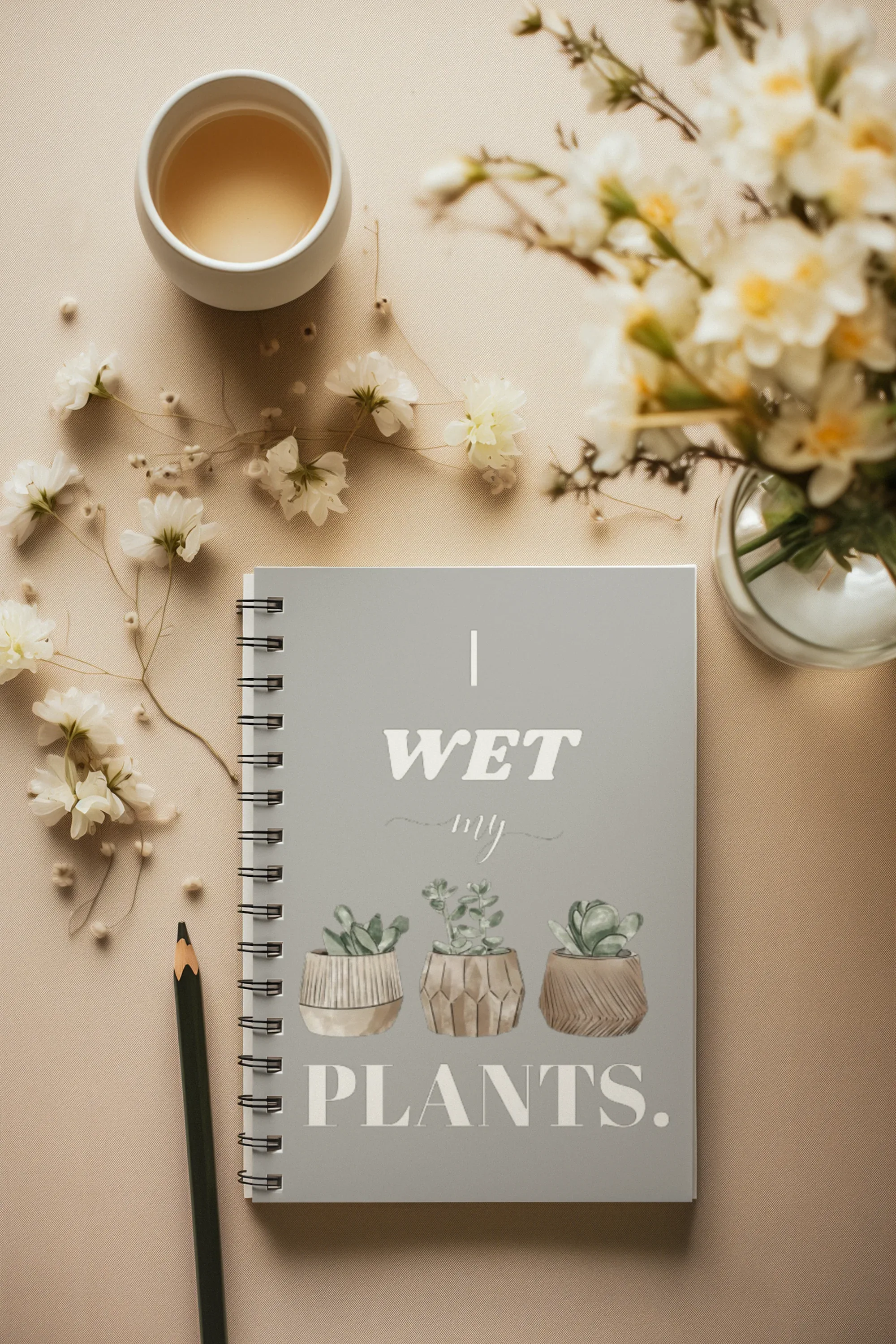 A5 spiral notebook with muted green cover, “I wet my plants” text and plant pot artwork.