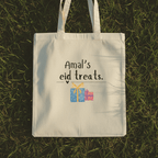 Off-white cotton tote bag with handles and “Amal’s eid treats” text and gift icons.
