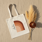 White cotton tote bag with terracotta abstract arch print and black signature on front