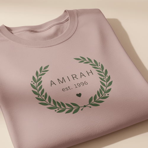 Mauve personalized name T-shirt with green floral wreath monogram reading “AMIRAH est. 1996”