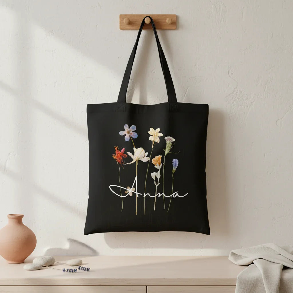 Black cotton tote bag with dried wildflower illustration and name "Anna".