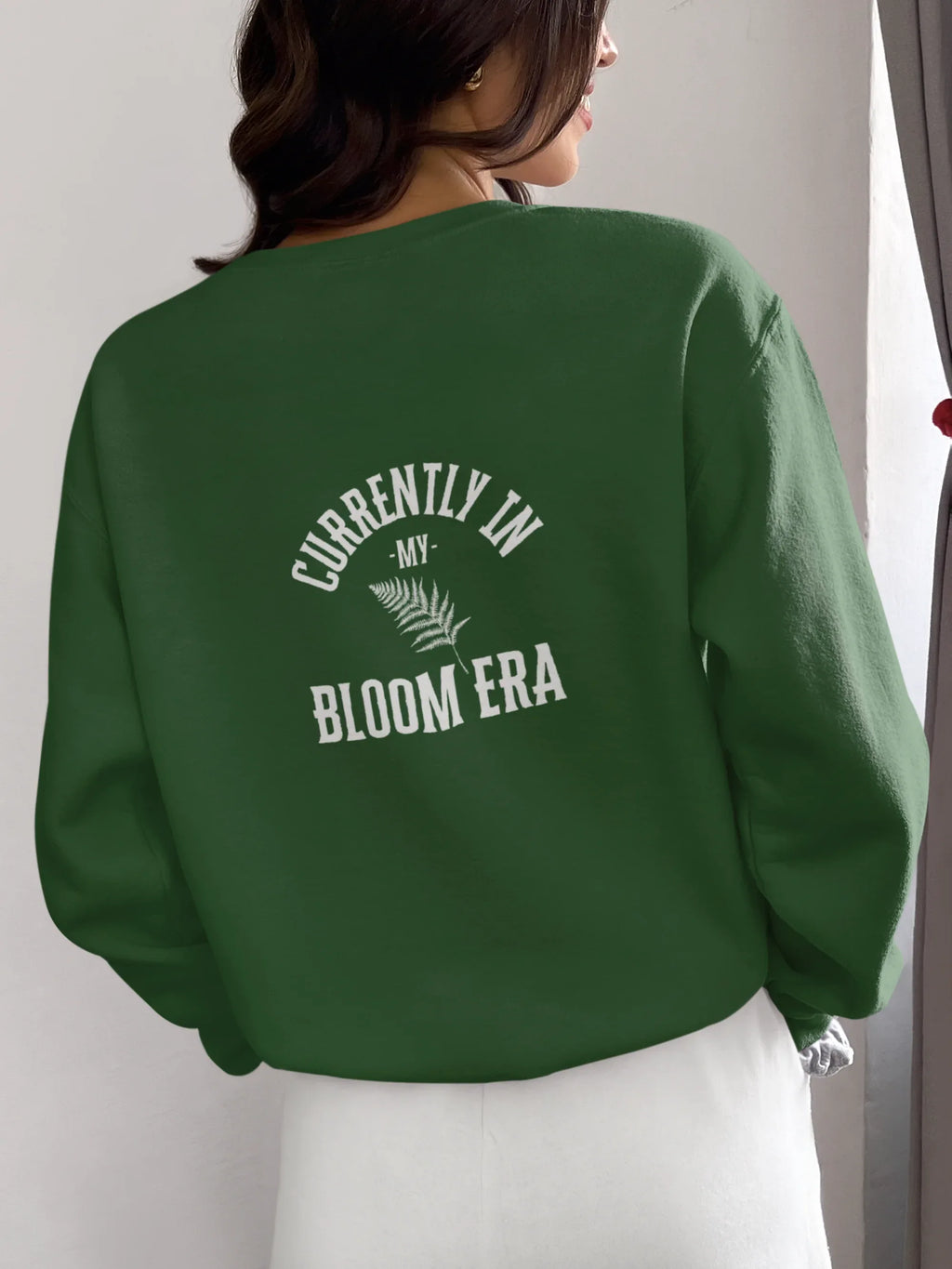Forest green sweatshirt with crew neck and "Bloom Era" back text print