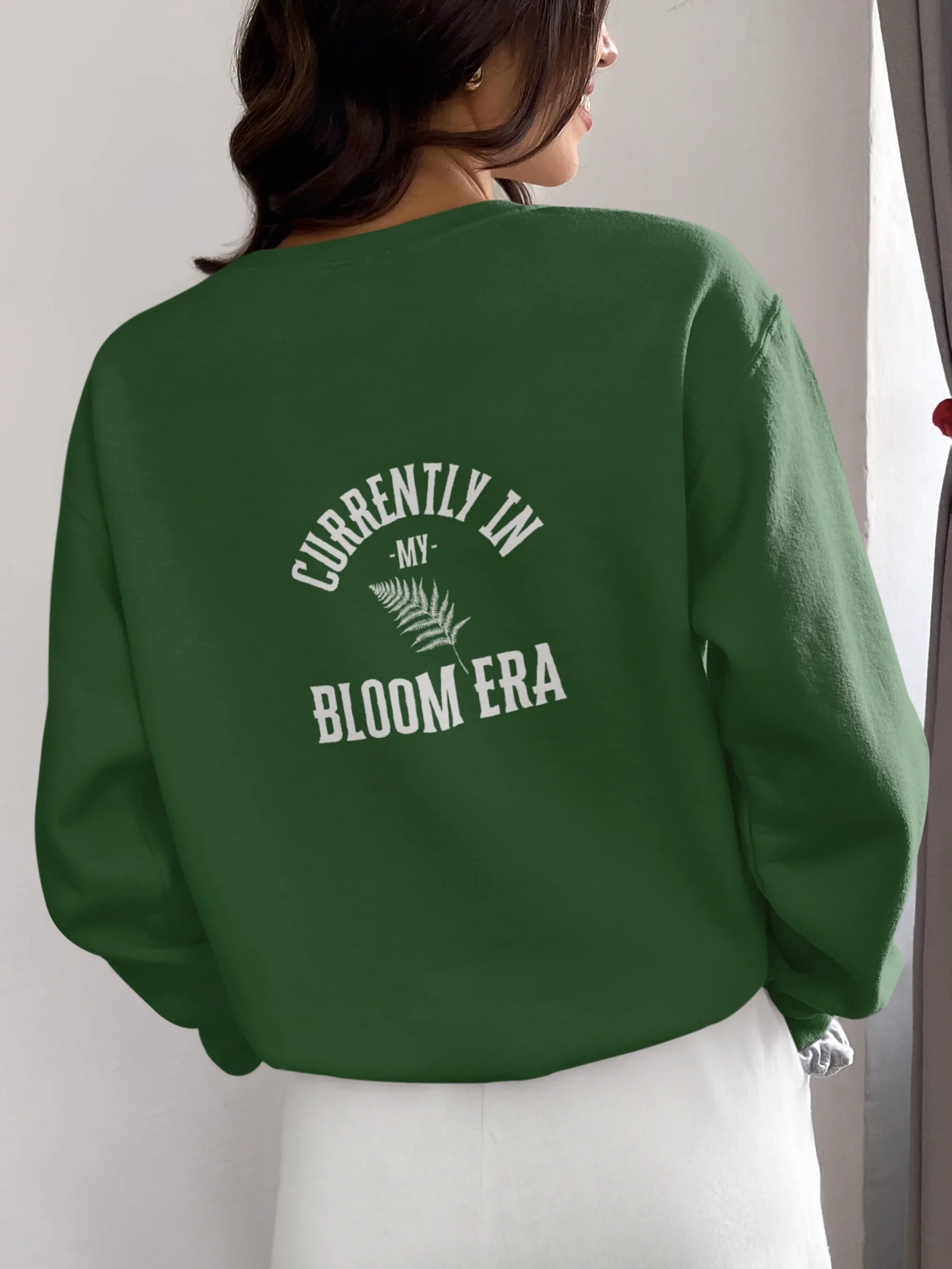 Forest green sweatshirt with crew neck and "Bloom Era" back text print