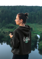 Black hoodie with kangaroo pocket and 'Just Breathe' logo on back, side view