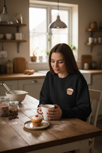Black crewneck sweatshirt with an embroidered cupcake on the front