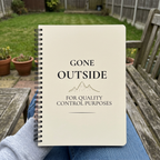 Beige Gone Outside notebook held on a garden bench
