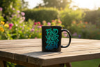 Black coffee mug with teal “Find Your Zen” print on wooden table in garden light