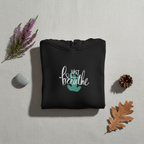 Black hoodie with “Just breathe” slogan and hand heart graphic on chest