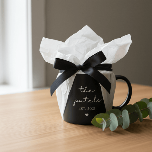 Black ceramic mug in gift wrap with ribbon; reads “the patels” and “EST 2021”