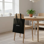 Black cotton tote bag with two short handles, printed “soft life”