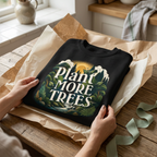 Black unisex sweatshirt with “Plant More Trees” graphic on the front, folded in paper.