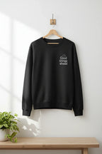 Black crewneck sweatshirt hanging on a wooden hanger with chest logo