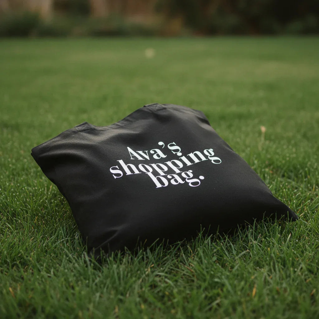 Black cotton tote bag with custom text reading “Ava’s shopping bag”.