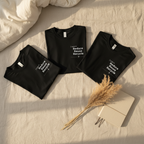 Black crew-neck T-shirts with Reduce Reuse Recycle graphic on bedding