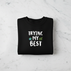 Black sweatshirt with 'TRYING MY BEST' quote and globe-and-leaves graphic