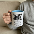 Blue climbing mug held naturally with a soft neutral sofa background