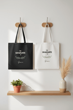 Two graduation tote bags side by side: black and white, “THE GRADUATE” and name Grace