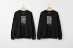 Two black crewneck sweatshirts with front slogan graphic hanging on hooks