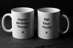 Two white coffee mugs, one says "Happy Birthday Though", the other "RIP Your Youth".