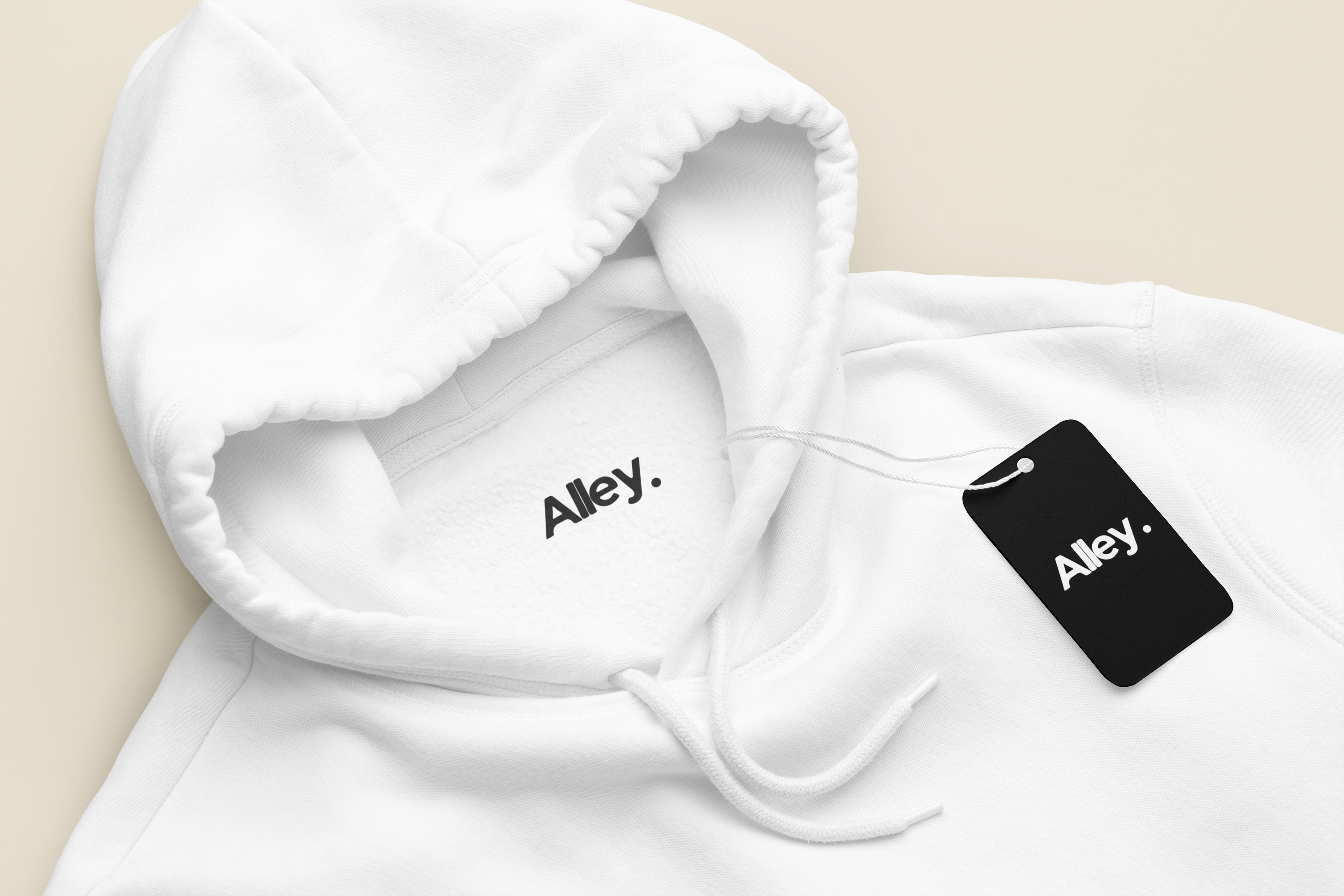 White hoodie close-up with hood strings and black “Alley.” hang tag