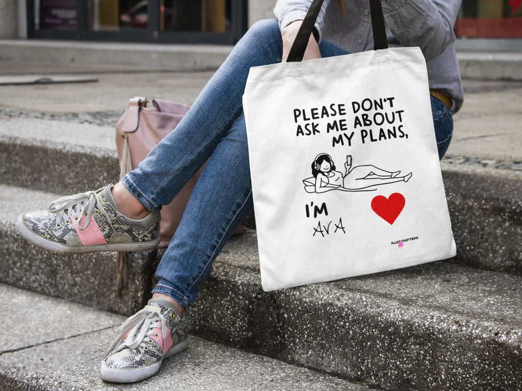 White canvas tote bag on steps with black straps, “Please don’t ask me about my plans” quote