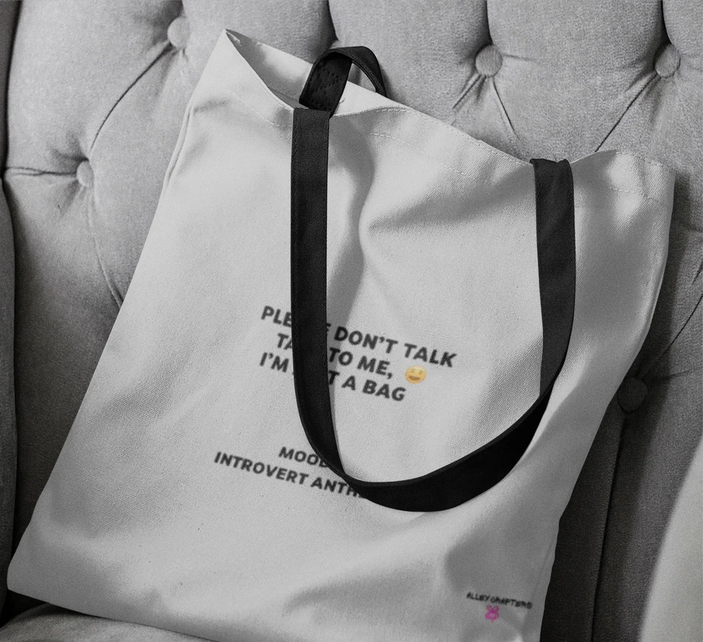 White tote bag close-up with black handles and front slogan print
