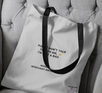 White tote bag close-up with black handles and front slogan print