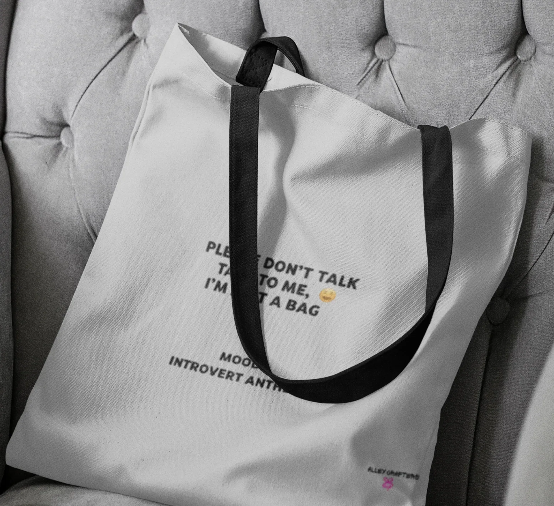 White tote bag close-up with black handles and front slogan print