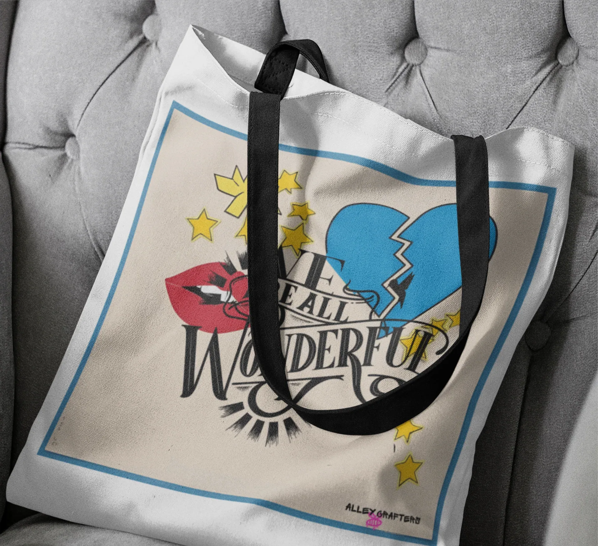 Close-up of light canvas tote bag front with black strap handles and Wonder graphic