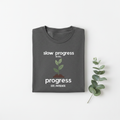Charcoal gray T-shirt with "slow progress" slogan and minimal plant graphic, crew neck.