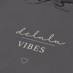 Charcoal hoodie fabric with “delulu VIBES” logo print and small heart detail