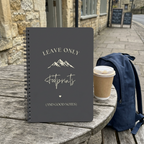 A5 hiking notebook with charcoal-gray cover, spiral binding, footprints and mountain text
