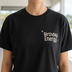 Black crewneck T-shirt with "Birthday Energy" text graphic and sparkle icons