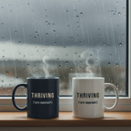 Two ceramic mugs, dark and white, printed with “THRIVING (Term dependant)”.