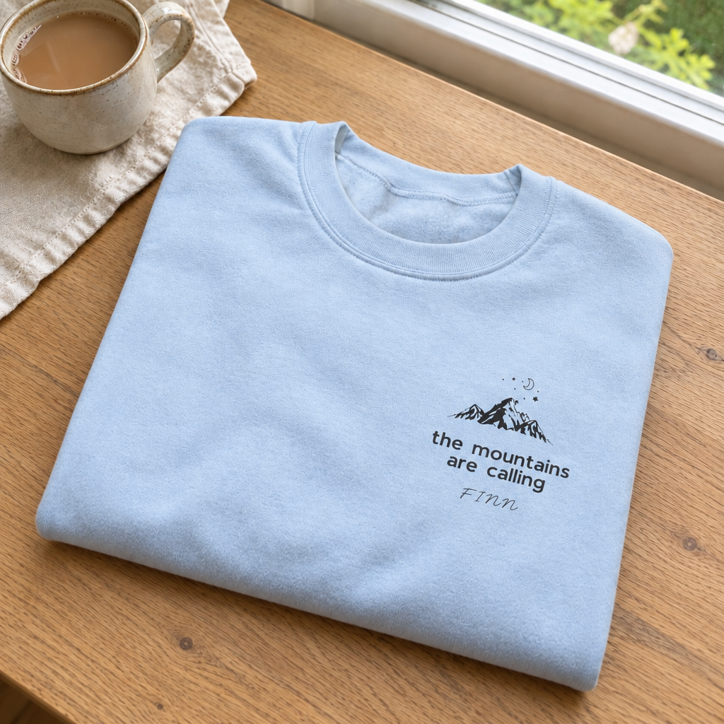 Close-up of light-blue Mountains Are Calling sweatshirt with Finn