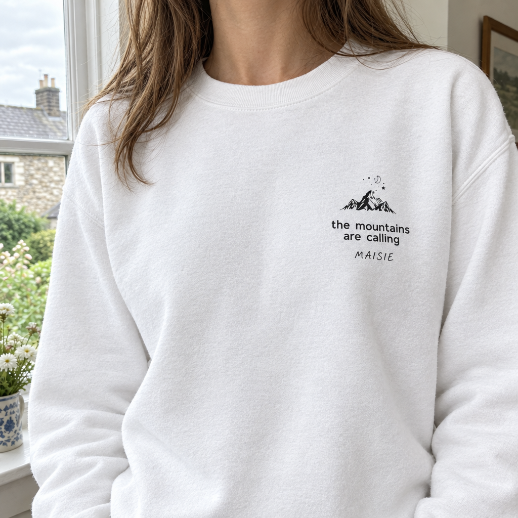 Close-up of white Mountains Are Calling sweatshirt with Maisie