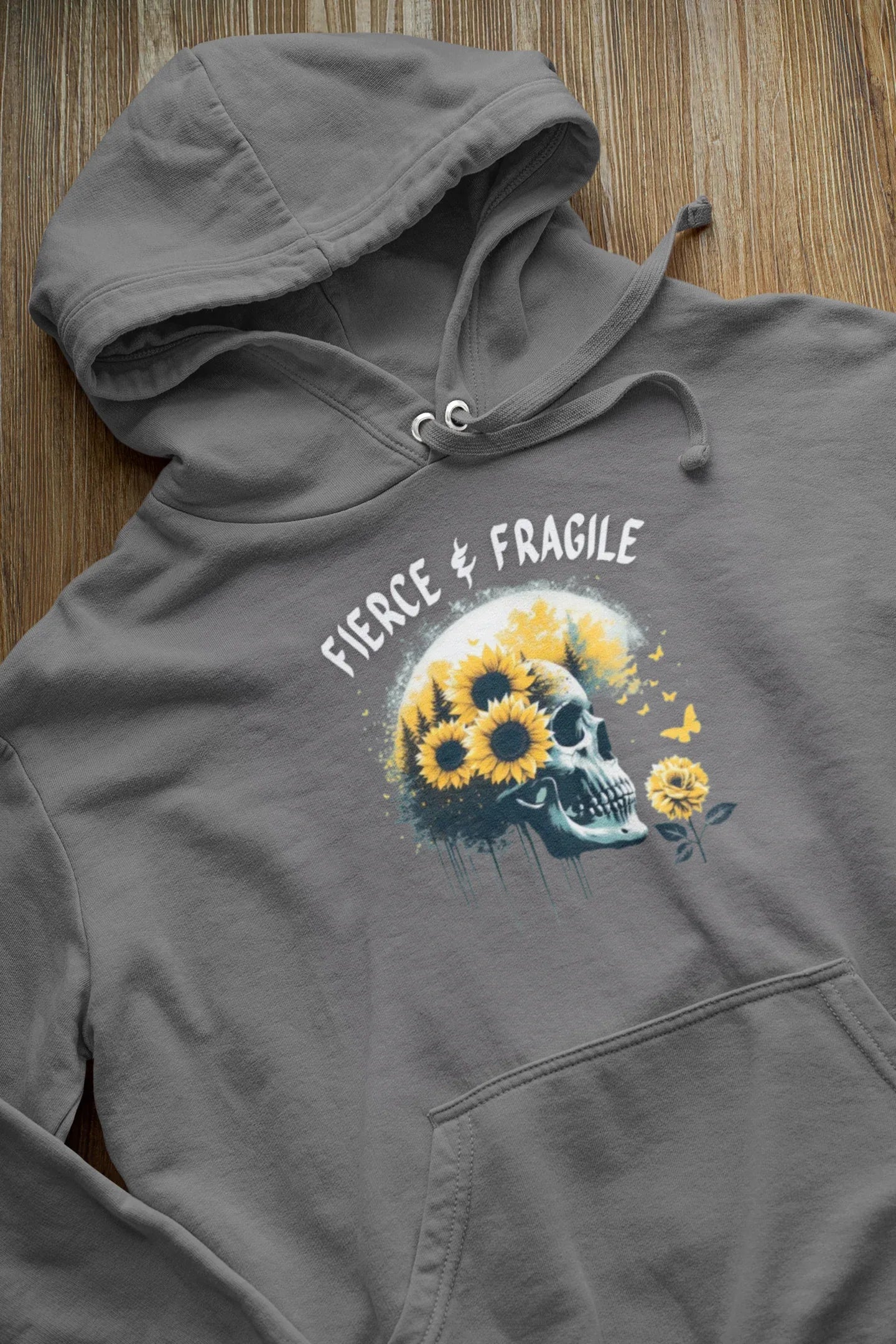 Gray hooded sweatshirt laid flat, featuring sunflower skull graphic and logo text