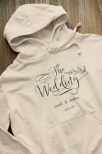 Cream wedding day hoodie sweatshirt with “The Wedding” logo print and drawstring hood