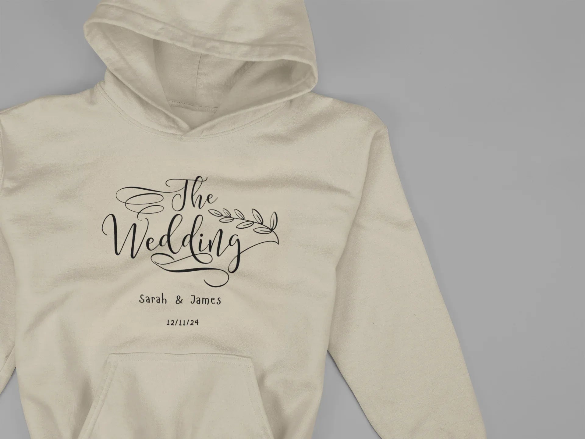 Cream wedding day hoodie sweatshirt with “The Wedding” logo print and front pocket