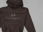 Dark brown unisex hoodie close-up, hood and pouch pocket with front line-art wedding graphic