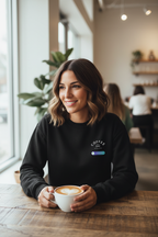 Black crewneck sweatshirt with “COFFEE” chest print and small multicolor badge