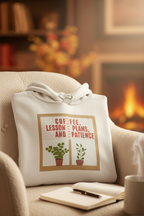 White hoodie on couch arm with front pouch pocket and potted plants graphic near a notebook