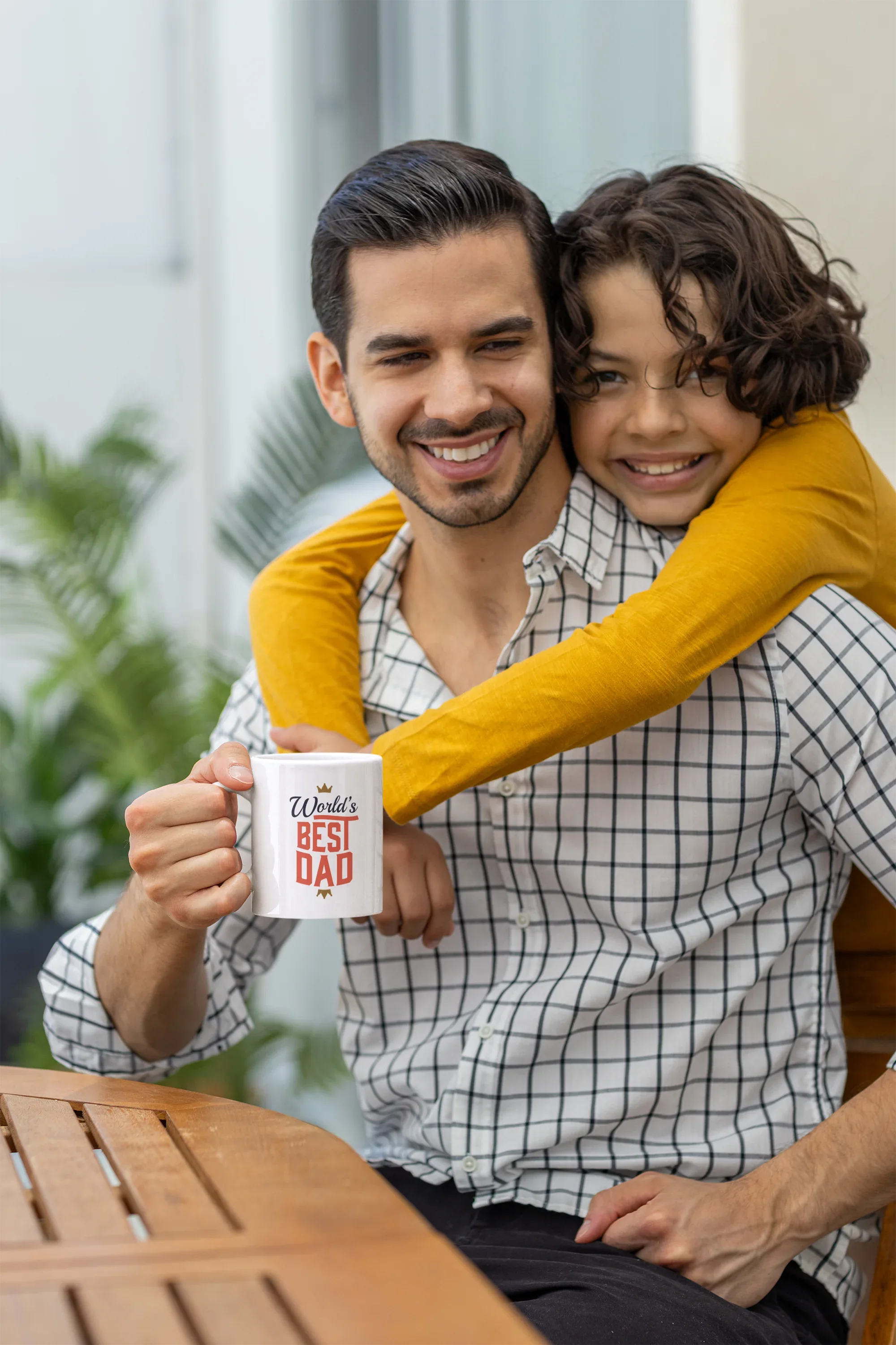 White mug with World's Best Dad crown and red letters, held in a smiling embrace.