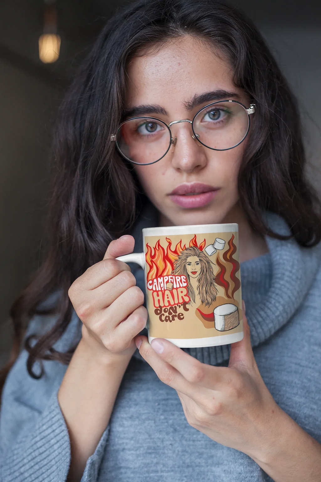 White ceramic mug with flame-haired woman graphic and coffee cup, held near face