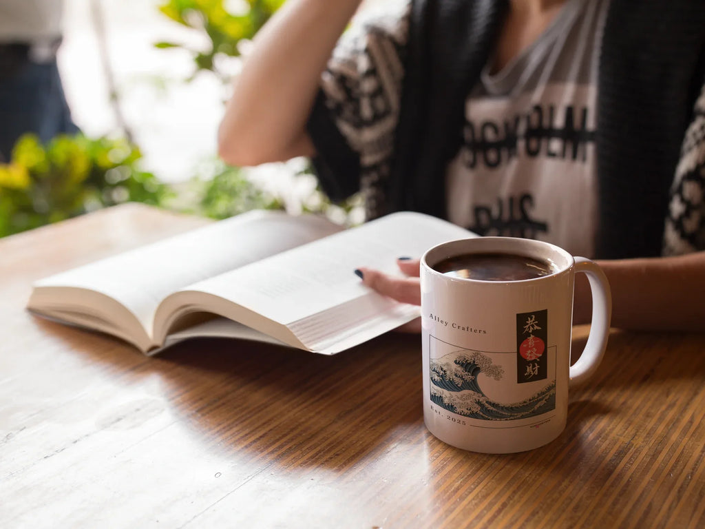 White mug with blue ocean wave print and red/black emblem, filled with coffee.